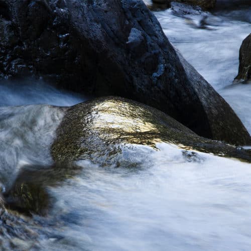 Pierre qui reflète la lumière du soleil dans une rivière avec des rochers autour