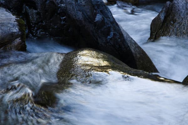 Pierre qui reflète la lumière du soleil dans une rivière avec des rochers autour