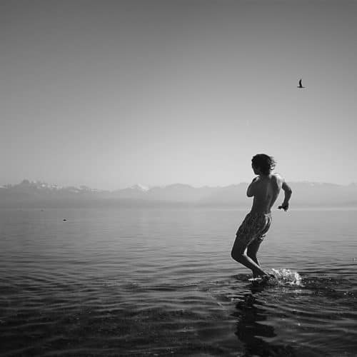 Jeune homme lançant des cailloux dans l'eau pour faire des ricochets