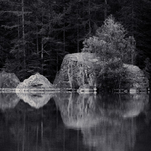 Rochers avec reflet dans l'eau d'un lac, apparence de glace en noir blanc