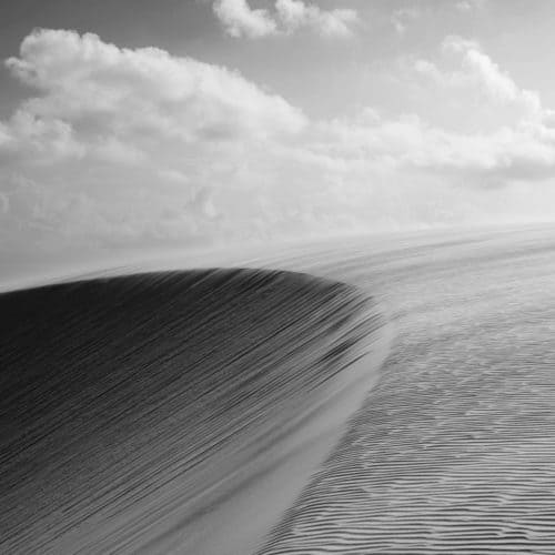 Dune de sable où le vent dessine de belles lignes et ciel avec nuages
