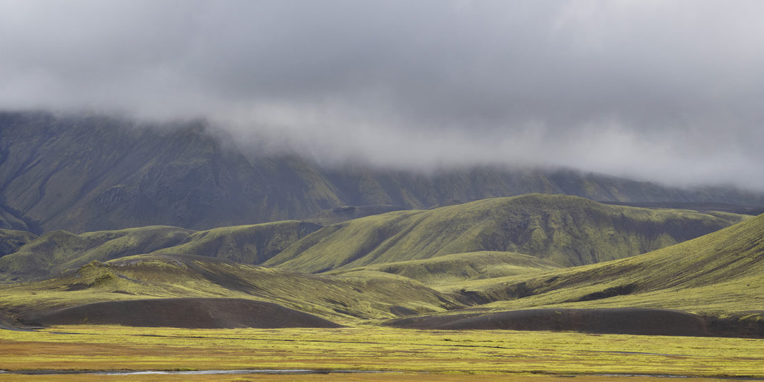 Plaine et montagne au fonds en couleurs jaune orange et vert dans le Landmannalaugar en Islande